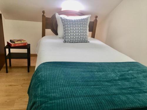 a bed with a green blanket and a pillow on it at Azurara Martins House in Azurara