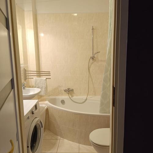 a bathroom with a tub and a toilet and a sink at Apartament Jana in Warsaw