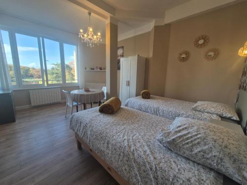 a bedroom with two beds and a table and a chandelier at Studio face au lac in Bagnoles de l'Orne