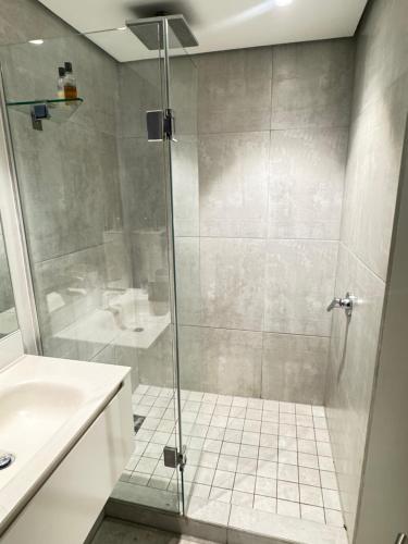 una doccia con una porta in vetro in un bagno di City Slick Hideaway a Città del Capo