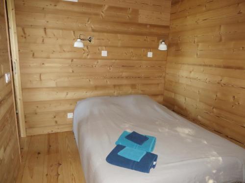 a small room with a bed in a wooden cabin at La Cabane aux Sapins in Ratières
