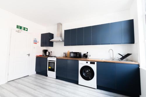 a kitchen with blue cabinets and a washing machine at The Albion Hotel in Hull