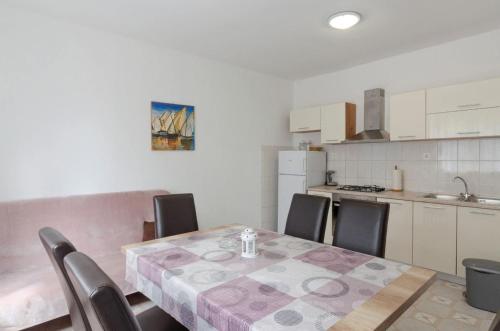 a dining room table with chairs and a kitchen at Guesthouse Karbuni (217) in Blato