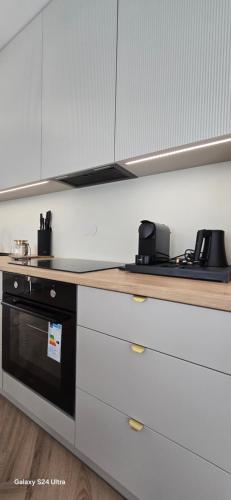 ブスコ・ズドロイにあるApartament MIRAGE NOWA DZIELNICAのキッチン(白いキャビネット、黒いオーブン付)
