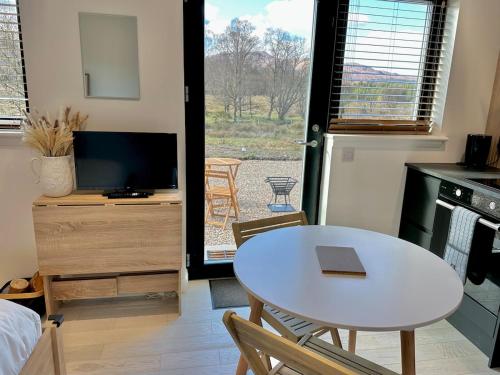 a living room with a table and a tv at Eco-Friendly Highland Suite with Mountain Views in Spean Bridge