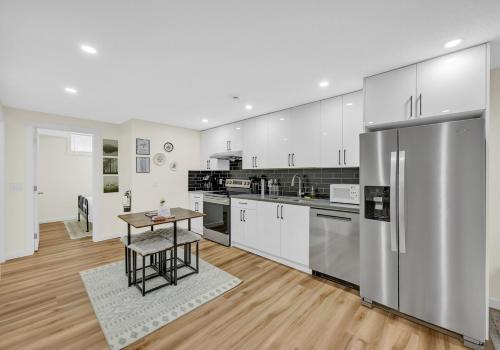 a large kitchen with white cabinets and a wooden floor at Brand New Private Secondary Suite in Mahogany in Calgary