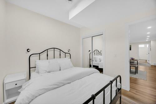 a white bedroom with a large bed and a mirror at Brand New Private Secondary Suite in Mahogany in Calgary