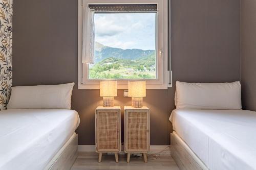 two twin beds in a room with a window at Gran Hogar Chic I 8 min de los remontes con balcón in La Massana
