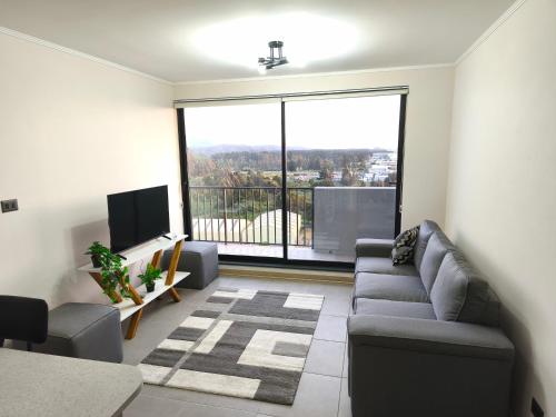 a living room with a couch and a large window at Departamento amoblado in San Pedro de la Paz