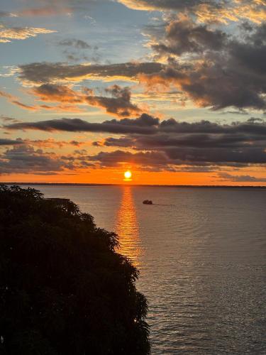 a sunset over the ocean with a boat in the water at Sumaúma Hotel in Tefé