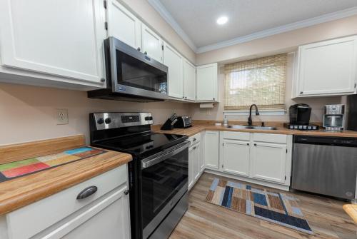 a kitchen with white cabinets and black appliances at 3-Bedroom Home with King Bed, Smart TVs & Fenced Yard in New Bern