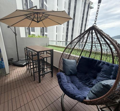 a hammock with a couch and a table and an umbrella at The Shore KK - Sunset Sea View Balcony Suite in Kota Kinabalu