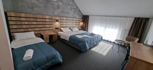 a hotel room with two beds and a desk at Sremsky inn in Stara Pazova