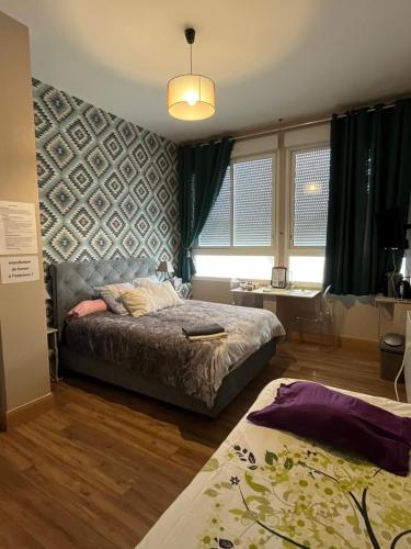 a bedroom with a bed and a table and windows at Hôtel Déco'lia-Soirée étape in Ballon