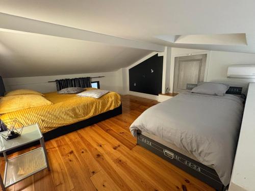 2 camas en una habitación con suelo de madera en Appartement à proximité d’Epinal avec climatisation, en Dogneville