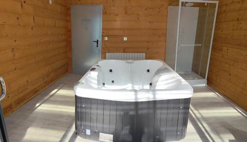 a large bath tub in a room with wooden walls at Mechanical cottage, old cars and bikes in Charmes
