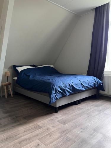 a bed with a blue comforter in a bedroom at Hoeve Herweijer in Strijensas