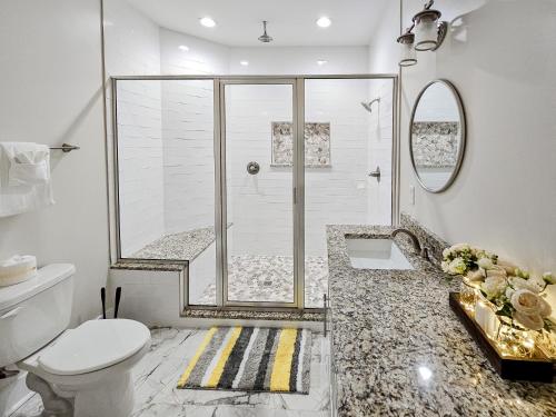 a white bathroom with a shower and a toilet at Brand New Home with Beach Views! Fully furnished 3 bedroom home in Gulfport in Gulfport