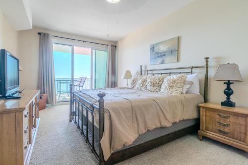 une chambre avec un lit et une télévision et un balcon dans l'établissement Beachview Condo in Legacy Tower 1 -1104 - fully furnished 2 bedroom 2 bath, à De Buys