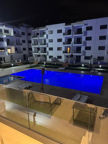 a swimming pool with blue water in a building at Residence Rmilat Garden Martil in Martil