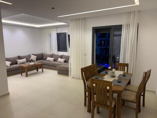 a living room with a table and a couch at Residence Rmilat Garden Martil in Martil