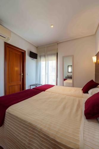 a bedroom with two beds with red and white sheets at Hostal Sol in Toledo