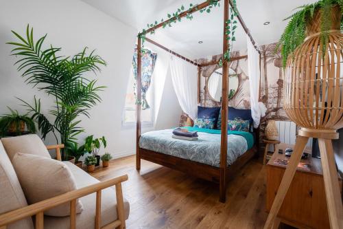 a bedroom with a canopy bed and plants at Studio Exotique Hyper-Centre Enghien 12min Paris in Enghien-les-Bains