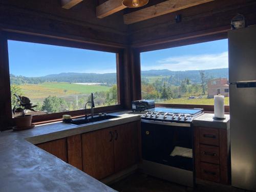 a kitchen with a stove and two large windows at Cabaña Alua in Ferrería de Tula