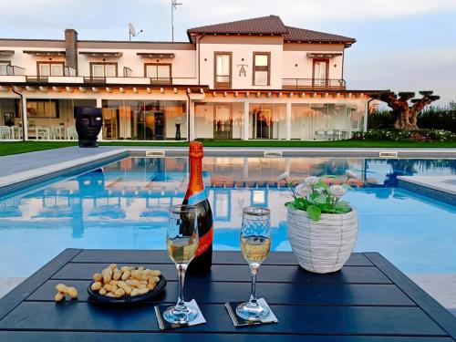 a table with two glasses of wine next to a pool at Hotel Ohana in Rome