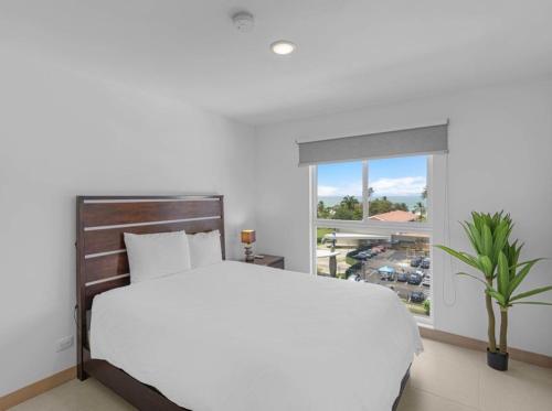 a white bedroom with a large bed and a window at Jacó Pacífico in Jacó