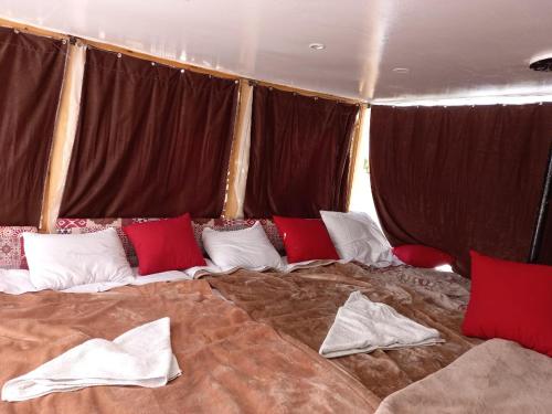 a large bed with red and white pillows on it at Traditional Felucca Sailing Boat Overnight in Aswan