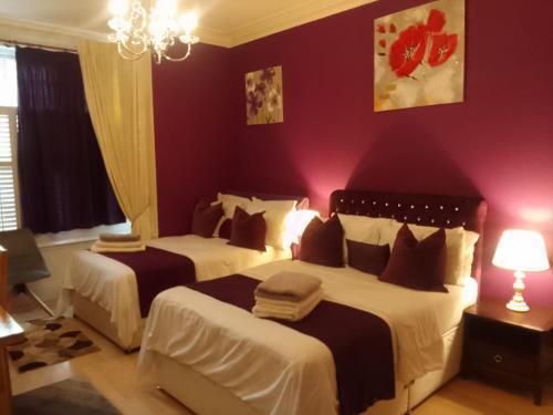 a bedroom with two beds and a red wall at Executive Suite at Ideal home & cottage, Inviting 2 Bedroom apartment, Sleep 6 Ideal for contractors, family & Groups in Birmingham