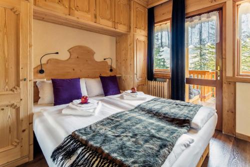una camera da letto con un grande letto con cuscini viola di Hotel Ciasa Lorenzi a Cortina dʼAmpezzo