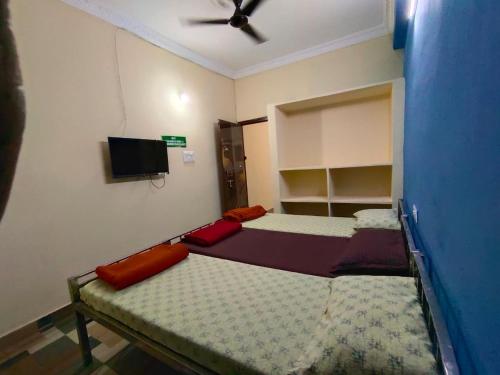 a small room with two beds and a ceiling fan at SriShivaShankari GuestHouse in Hyderabad