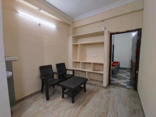 a room with two chairs and a table and shelves at SriShivaShankari GuestHouse in Hyderabad