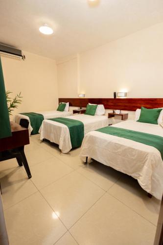 a room with three beds with green sheets at Tariri Hotel in Pucallpa