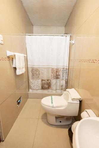 a white bathroom with a toilet and a shower at Tariri Hotel in Pucallpa