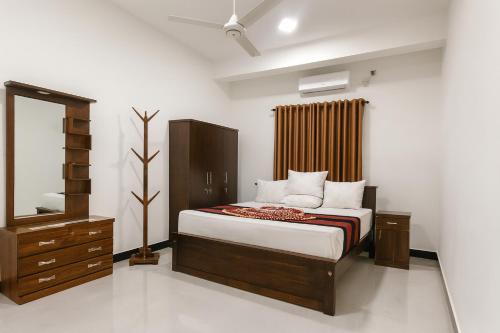 a bedroom with a bed with a dresser and a mirror at ACCOM Premium Residence in Gangodawila