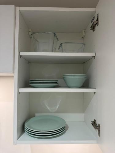 a white cabinet with plates and bowls in it at Cosy Modern 2 Beds Chorley Center in Chorley
