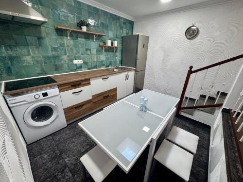 eine Küche mit einer Waschmaschine und einem weißen Tisch in der Unterkunft Punta Garo in Punta de Mujeres