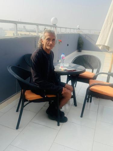 un uomo seduto a un tavolo su un balcone di Phoenix Pyramids View Inn a Il Cairo