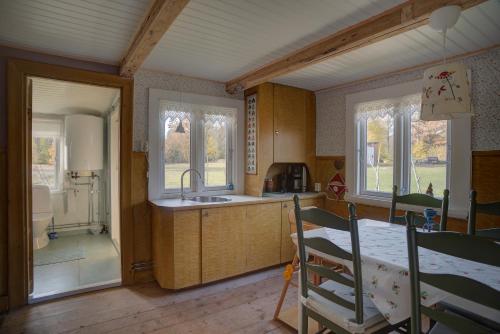 a kitchen with a table and a sink and windows at Sommargyllen Torp Brändabo in Torsås