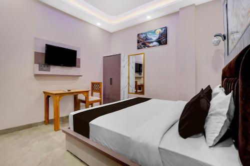 Un dormitorio con una cama, un escritorio y un televisor. en Hotel O Shauryam, en Kankhal