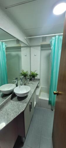 une salle de bain avec deux lavabos et un grand miroir dans l'établissement Departamento Plaza San Martín, à Córdoba