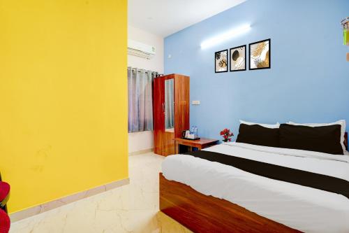 Un dormitorio con una cama grande y una pared amarilla. en Hotel O R R Comforts Boarding and Lodging, en Nelamangala