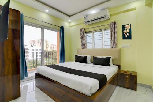 a bedroom with a bed and a large window at Hotel O Jerry Guest House & Caf� By CheckIn in Bishnupur