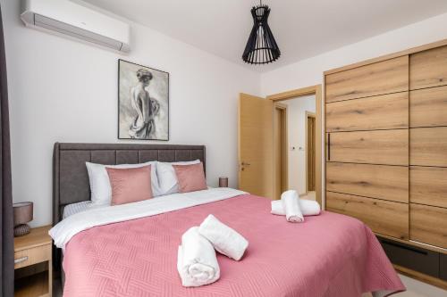 ein Schlafzimmer mit einem rosa Bett mit zwei Handtüchern darauf in der Unterkunft Mira Bay in Igalo