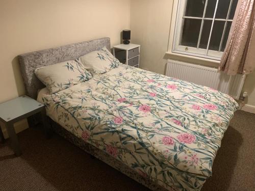 a bedroom with a bed with a floral comforter at Burton Down Town Apartment in Burton upon Trent
