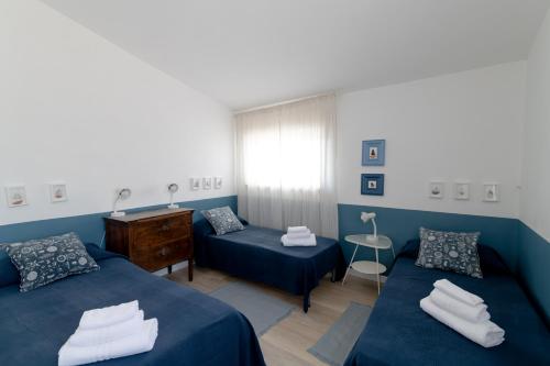 ein blaues Zimmer mit zwei Betten und einem Klavier in der Unterkunft Verde Blu Lakefront Boutique Holiday Apartments Trevignano Romano in Trevignano Romano