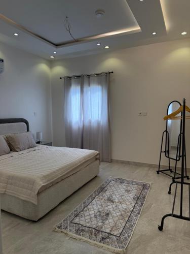 a white bedroom with a bed and a window at Apartment in Tabuk